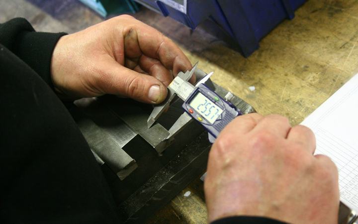 Hands measuring a metal part with a digital caliper